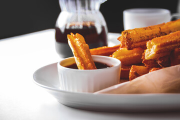Traditional Spanish treat street fast food churros on a plate with hot chocolate sauce.