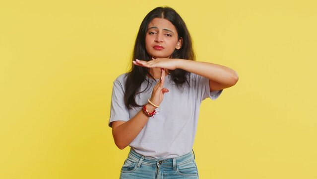 Tired serious upset Indian young woman showing time out gesture, limit or stop sign, no pressure, I need more time, take a break, relax, rest, help. Arabian girl isolated on yellow studio background