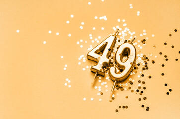 49 years birthday celebration festive background made with golden candle in the form of number Forty nine lying on sparkles.