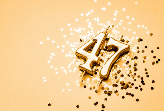 47 years birthday celebration festive background made with golden candle in the form of number Forty seven lying on sparkles.