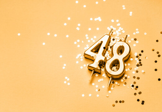 48 years birthday celebration festive background made with golden candle in the form of number Forty eight lying on sparkles.