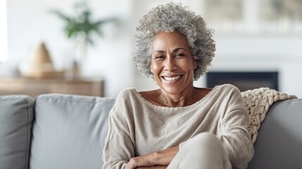 A content older woman embraces relaxation on her living room couch. - obrazy, fototapety, plakaty