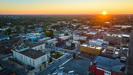Yellow sun rising at dawn over Muncie IN downtown buildings and courthouse, sunrise aerial