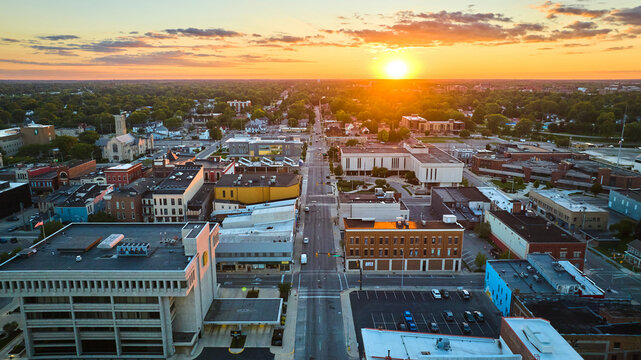 Golden sun setting on horizon of Midwest downtown, Muncie city aerial, IN at sunset