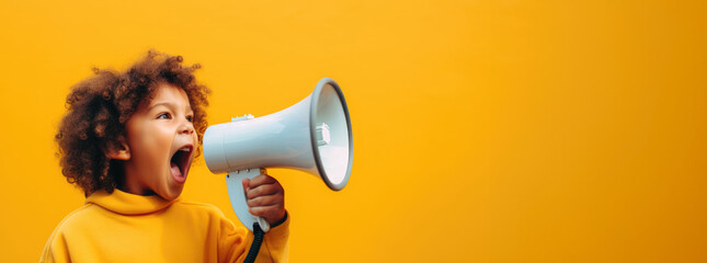 young boy in a yellow hoodie loudly announcing discounts and sales in a children's store through a megaphone - obrazy, fototapety, plakaty