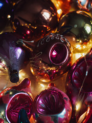 Vertical close up of vintage blown glass Christmas ornaments illuminated with electric lights.