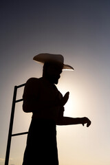 Silhouette of a giant Cowboy statue againts the sun in Mojave Desert along the U.S. Route 66,...