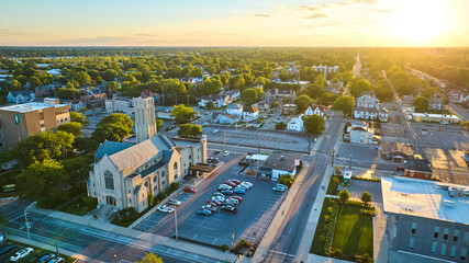 Church in Midwest town at sunset with golden glow and neighborhood, Muncie, IN aerial