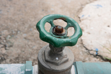 The old water valve is a mountain color and behind it is a concrete floor.