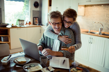 Middle aged couple holding credit card in the kitchen