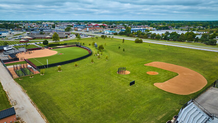 Obraz premium Varsity Softball Complex aerial with players practicing on field and distant buildings, Muncie, IN