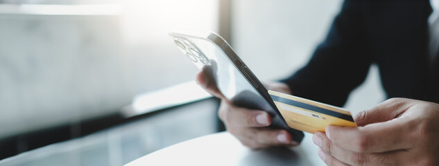 Online payment,Man's hands holding a credit card and using smart phone for online shopping-panoramic banner.