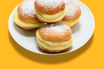 Obraz na płótnie Canvas three bakery dreams on a white plate against a yellow background.