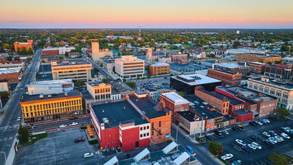 Midwest city downtown aerial at sunset, Muncie, Indiana with buildings and pink sky