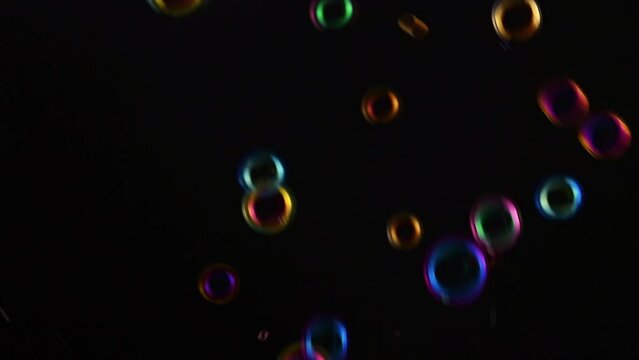 Soap bubble background. Colorful soap bubbles fly across black background. slow motion