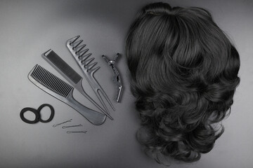 Hairdresser tools close-up isolated on black background. Curls of dark brunette hair and a set of...