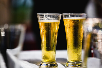 A glass of beer on table with blur light gold bokeh at relax moment in restaurant.