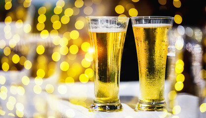 A glass of beer on table with blur light gold bokeh at relax moment in restaurant.