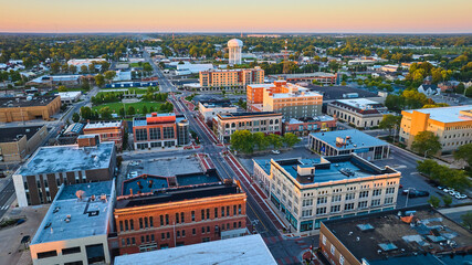 Downtown Muncie Indiana aerial at dawn with yellow sunrise lighting on buildings and water tower