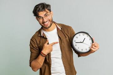 It is your time, hurry up. Indian young man showing time on wall office clock, ok, thumb up,...