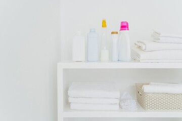 Neatly organized laundry shelf with clean towels and various detergents - obrazy, fototapety, plakaty