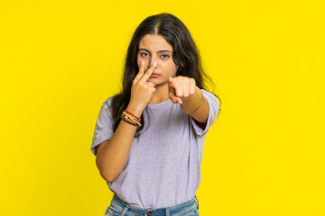 I am watching you. Confident attentive woman pointing at her eyes and camera, show I am watching you gesture spying on someone. Pretty disappointed Indian girl isolated on yellow studio background - obrazy, fototapety, plakaty