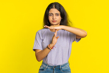 Tired serious upset Indian young woman showing time out gesture, limit or stop sign, no pressure, I need more time, take a break, relax, rest, help. Arabian girl isolated on yellow studio background - obrazy, fototapety, plakaty