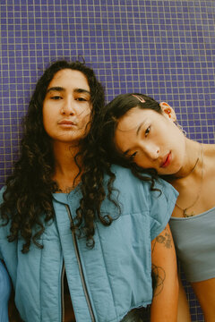 Vintage portrait of two multiracial non-binary friends posing and looking into camera