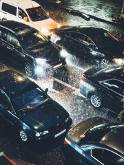 Traffic jam at night city during rain, many cars go slow in storm, vertical image.