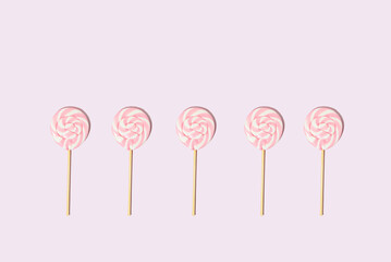 Pink lollipops on a pink background with copy space. Flat lay. Christmas candy monochrome concept.