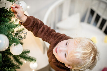 Little girl looking at Christmas tree while standing in crib