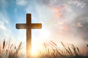 The cross on grass with sunset in the sky background