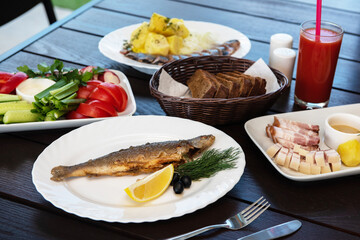 Fried grayling fish on a palte with greens and lemon