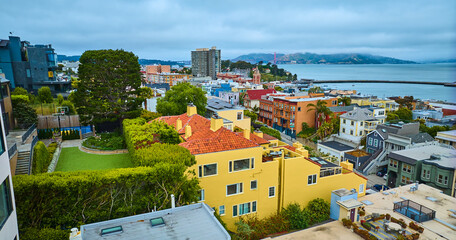 Bright yellow San Francisco apartment building with green roof and distant Aquatic Cove aerial, CA