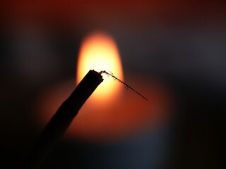 Incense stick burning with candle flame background 