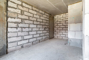 Renovation of a room in a modern house under construction. The walls are made of cement masonry. Cement floor screed.