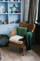 Wicker armchair with a pillow and a green plaid at a blue cafe with a Christmas decor