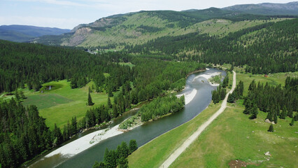 Aerial view of a green mountain landscape and alpine meadows where a river flows from the mountains...