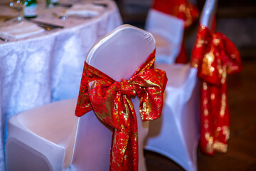 Christmas dinner table set up in restaurant with festive ornaments, decorations, red chair bows and tableware