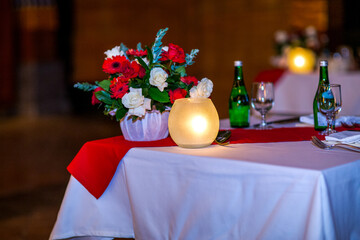 Christmas dinner table set up in restaurant with festive ornaments, decorations, red chair bows and tableware