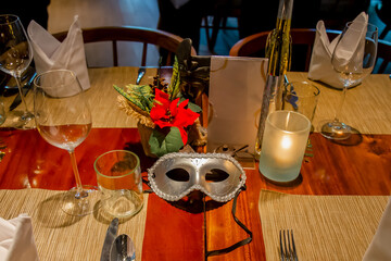 Christmas dinner table set up in restaurant with festive carnival masks, ornaments, decorations and tableware