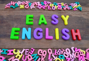 Easy English phrase on an old wooden table. Many plastic letters of the English alphabet. English language training