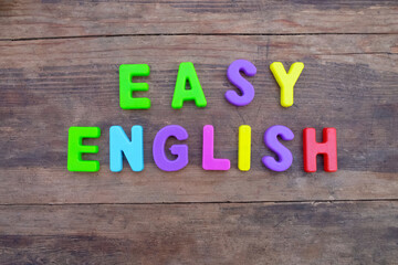 The inscription "Easy English" on a wooden surface in colored plastic letters