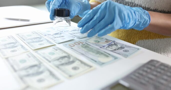 Expert with gloves checks authenticity of banknotes through magnifying glass. Counterfeit money concept