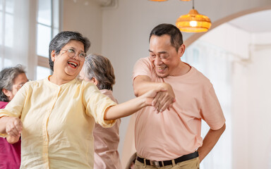 Selective focus Asian senior elderly woman dancing with friends, wearing casual clothes, staying in indoor cozy home at living room, smiling with happiness. Retirement, Lifestyle, Healthcare Concept.