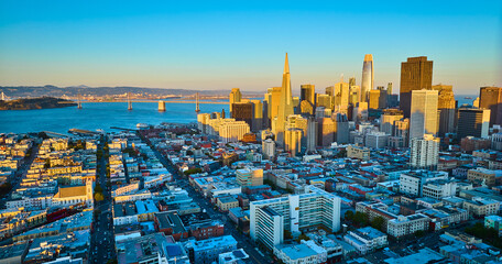 San Francisco city sunset aerial above buildings with some in shadow and golden skyscrapers, CA