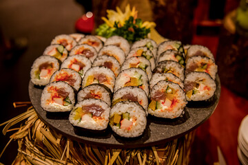 Sushi bar among catering banquet table. Variety of snacks, appetizers, seafood and cooked meals displayed as buffet for wedding, Christmas, business corporate, birthday party or other event