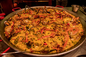 Classic Spanish paella with shrimps, clamps, mussels in traditional pan displayed on buffet line in restaurant for catering wedding, birthday party or other event