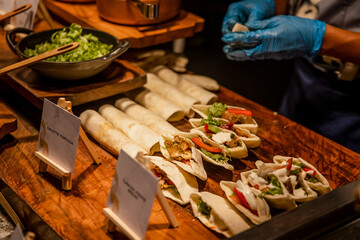 Close up of chef's hands preparing Peking duck in restaurant. Cutting meat and making pancakes with spring onions and other vegetables, spices and sweet bean sauce to serve customers