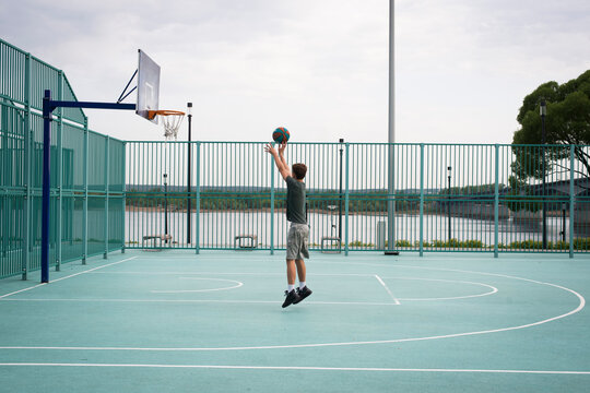 Boy teenager playing basketball at city playground. Active life, hobby, sports for children